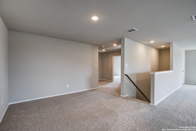 empty room with carpet floors, recessed lighting, visible vents, and attic access