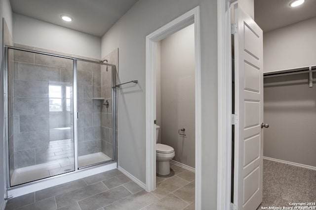 bathroom featuring baseboards, a stall shower, toilet, and a spacious closet
