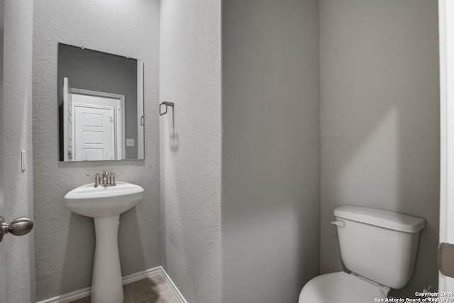 half bath featuring a sink, tile patterned floors, and toilet