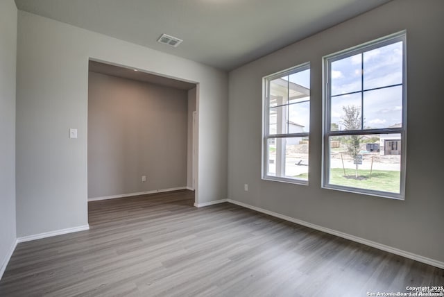 spare room with baseboards, visible vents, and wood finished floors