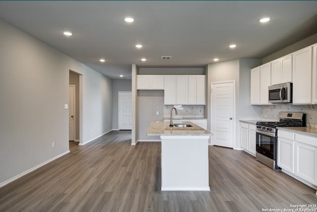 kitchen featuring a sink, appliances with stainless steel finishes, wood finished floors, and tasteful backsplash