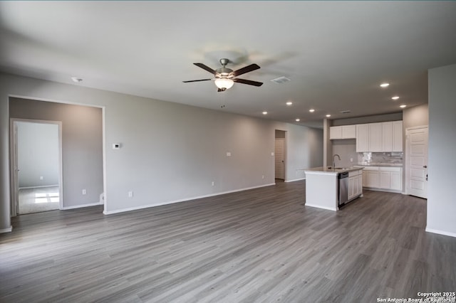 unfurnished living room with a ceiling fan, a sink, baseboards, dark wood-style floors, and recessed lighting