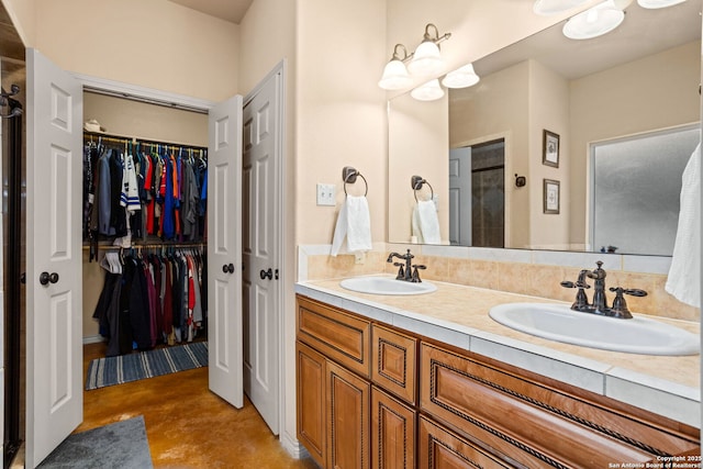 full bathroom with a walk in closet, concrete floors, and a sink