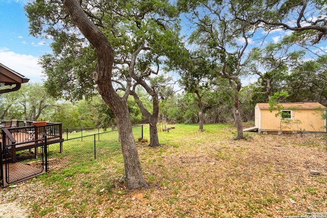 view of yard with a storage shed, fence, an outbuilding, and a wooden deck