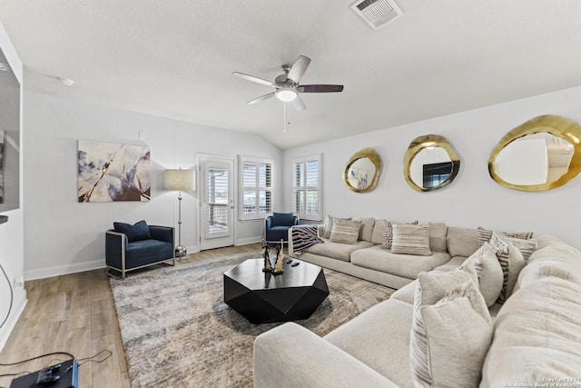 living room featuring ceiling fan, baseboards, wood finished floors, vaulted ceiling, and visible vents