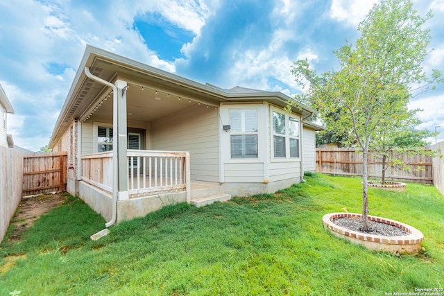 back of house with a fenced backyard and a yard
