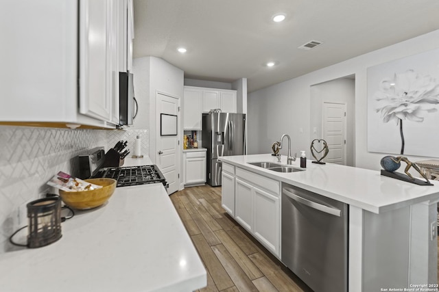 kitchen featuring decorative backsplash, wood finished floors, light countertops, a sink, and appliances with stainless steel finishes