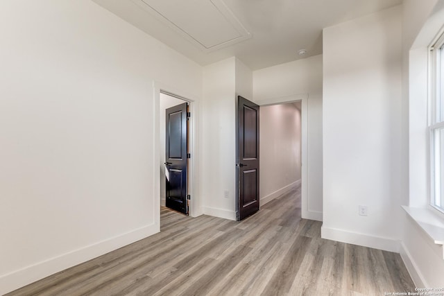 empty room with baseboards, attic access, and light wood-type flooring