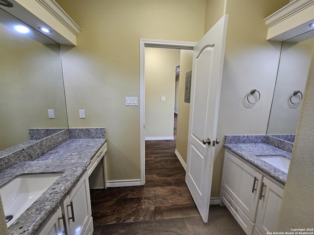 bathroom with a sink, baseboards, wood finished floors, and two vanities