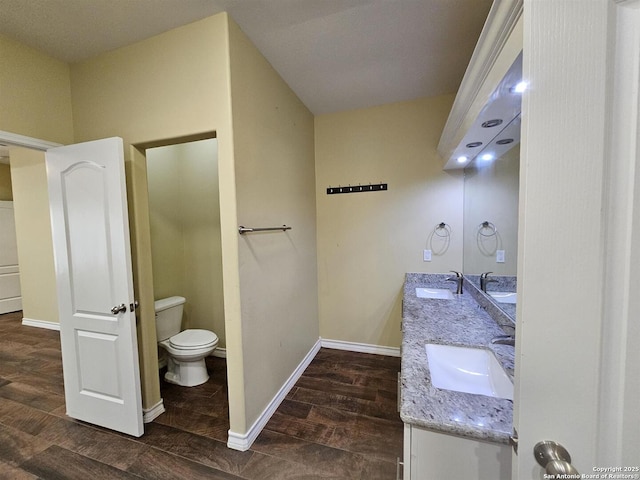 bathroom featuring toilet, baseboards, and a sink