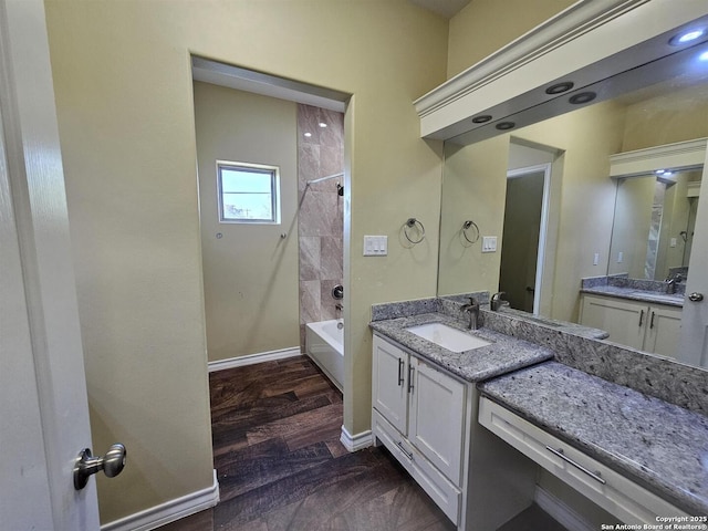 bathroom featuring shower / bathtub combination, baseboards, two vanities, and a sink