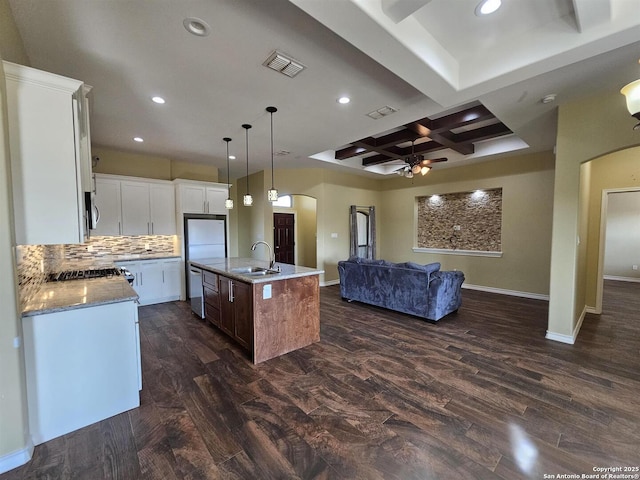 kitchen featuring a sink, arched walkways, ceiling fan, and open floor plan