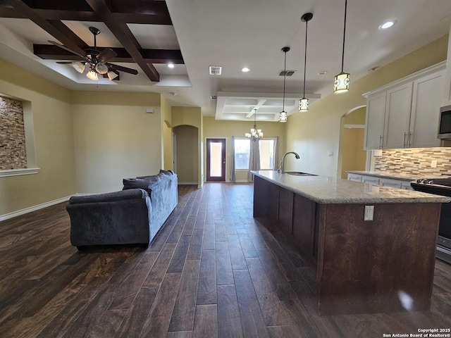 kitchen with appliances with stainless steel finishes, a sink, arched walkways, ceiling fan with notable chandelier, and coffered ceiling