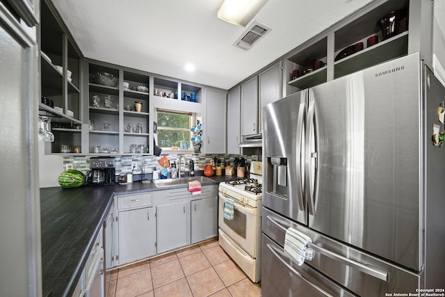 kitchen featuring stainless steel refrigerator with ice dispenser, visible vents, open shelves, a sink, and white range with gas stovetop