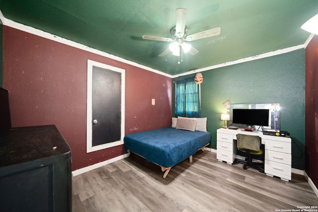 bedroom featuring baseboards, a textured wall, ceiling fan, and wood finished floors