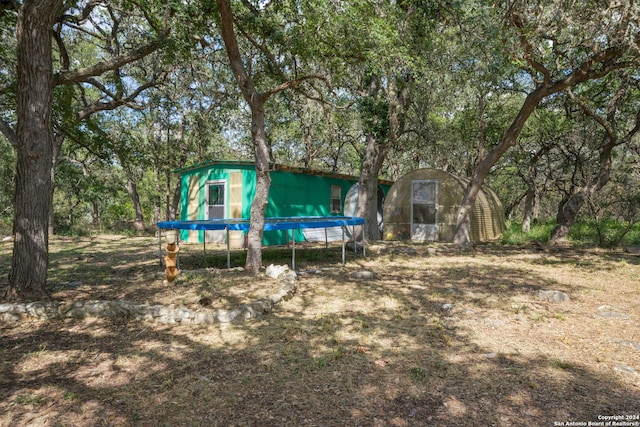 back of house featuring an outdoor structure and a trampoline