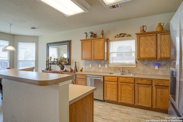 kitchen with a sink, appliances with stainless steel finishes, decorative backsplash, and light countertops