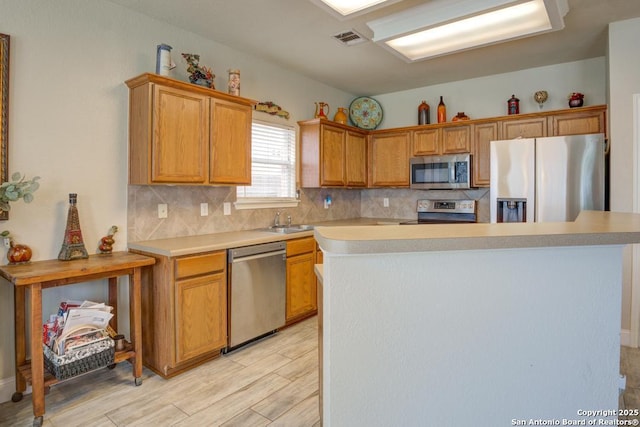 kitchen with a kitchen island, visible vents, appliances with stainless steel finishes, tasteful backsplash, and light countertops