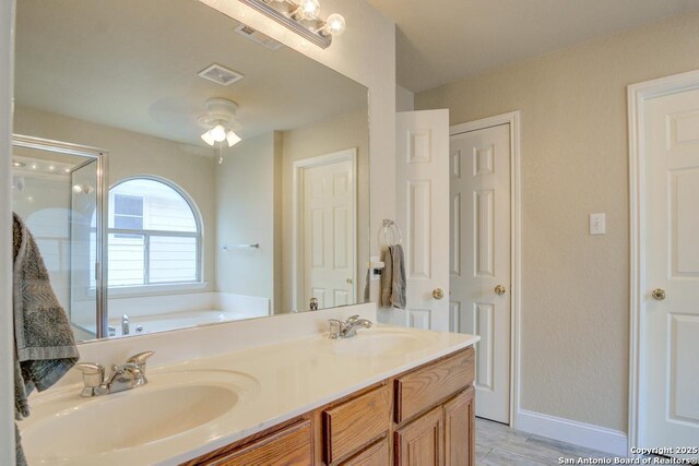 bathroom with double vanity, a shower stall, a sink, and a garden tub