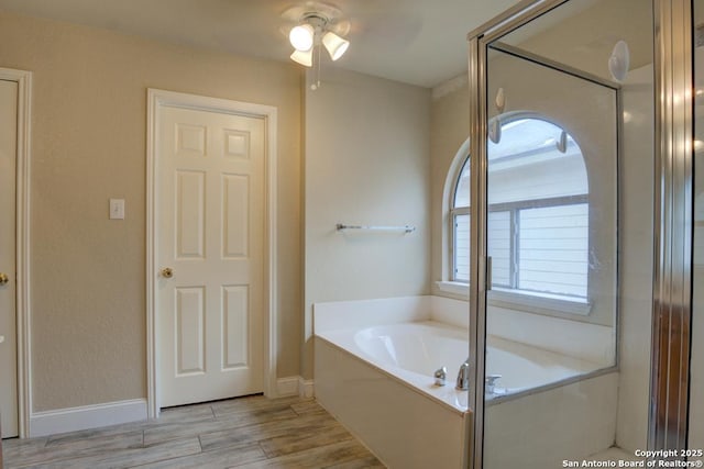full bath featuring baseboards, ceiling fan, a garden tub, and wood finished floors