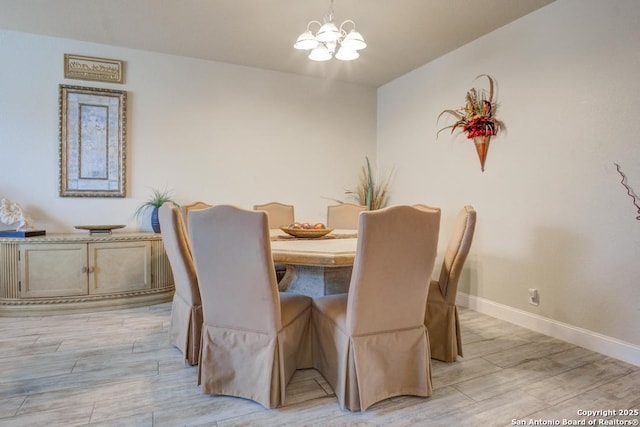 dining area with baseboards, an inviting chandelier, and light wood-style flooring