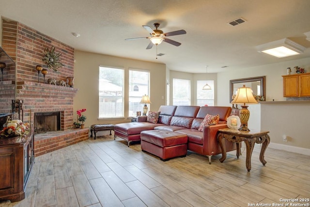 living room featuring baseboards, ceiling fan, a brick fireplace, and light wood-style flooring
