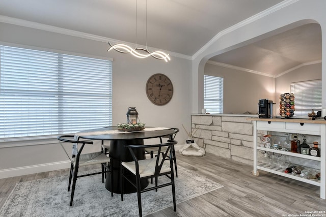 dining area featuring crown molding, arched walkways, and wood finished floors
