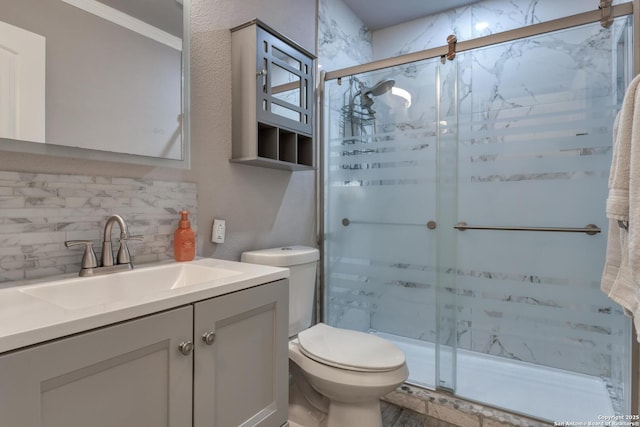 bathroom with vanity, toilet, decorative backsplash, and a stall shower