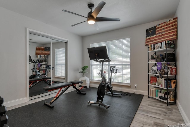 workout area with light wood-style floors, baseboards, and ceiling fan