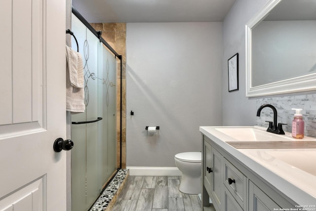 full bath featuring vanity, decorative backsplash, baseboards, and a shower stall