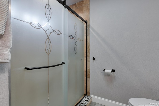 full bathroom featuring baseboards, toilet, and a shower stall