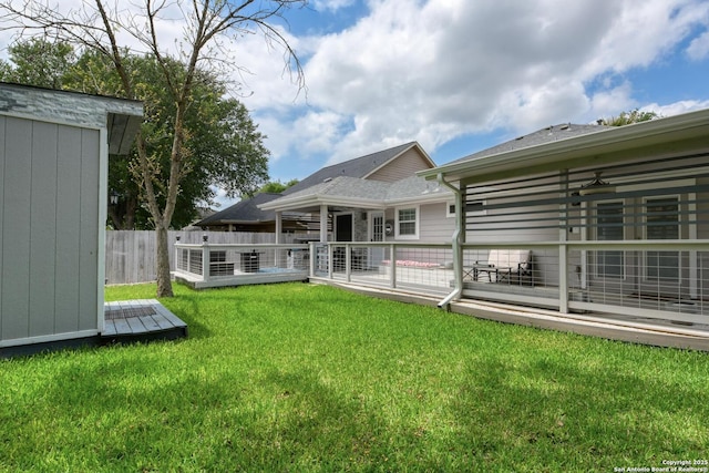 rear view of property with a yard, a deck, and fence