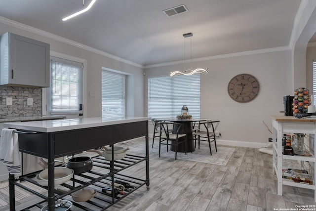 dining area with an inviting chandelier, light wood-style flooring, baseboards, visible vents, and ornamental molding