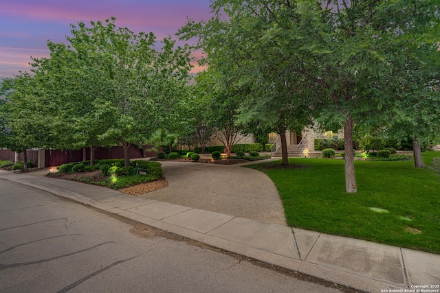 view of property hidden behind natural elements featuring fence and a yard