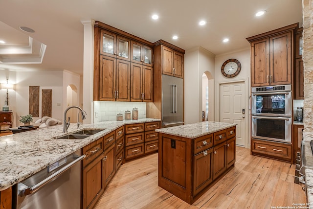kitchen with arched walkways, appliances with stainless steel finishes, a sink, light wood finished floors, and ornamental molding