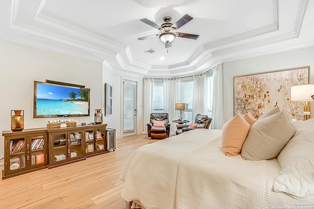 bedroom with crown molding, a tray ceiling, visible vents, and light wood-type flooring