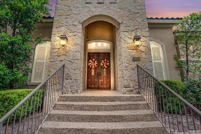view of exterior entry featuring stucco siding and stone siding