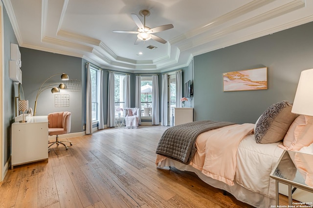 bedroom with visible vents, crown molding, baseboards, light wood-type flooring, and a raised ceiling