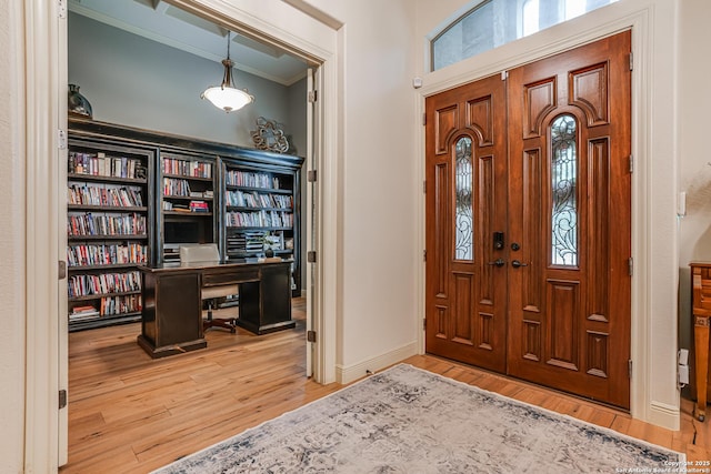 foyer entrance featuring crown molding, wood finished floors, and a healthy amount of sunlight