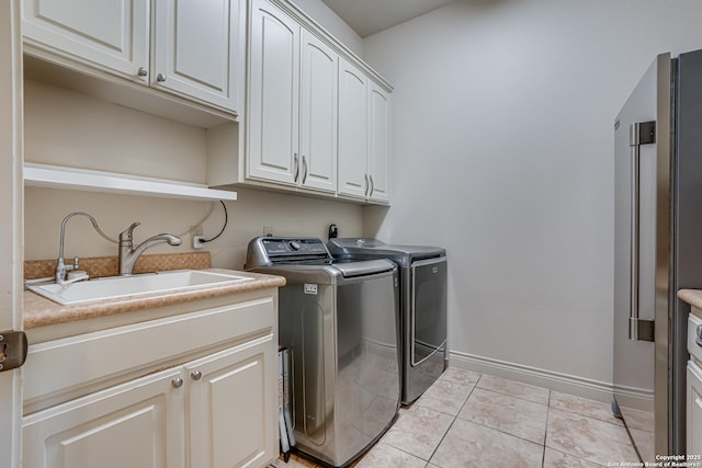 laundry area with cabinet space, washer and dryer, a sink, baseboards, and light tile patterned floors