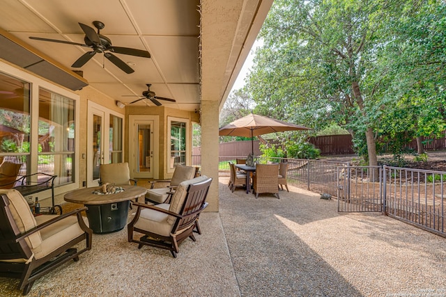 view of patio featuring a fenced backyard, outdoor dining space, ceiling fan, and an outdoor fire pit