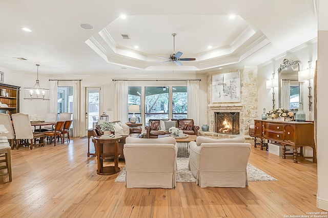 living area featuring ceiling fan, a stone fireplace, visible vents, light wood finished floors, and ornamental molding