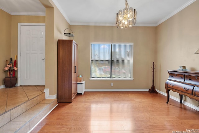living area with light wood-style floors, ornamental molding, baseboards, and a chandelier