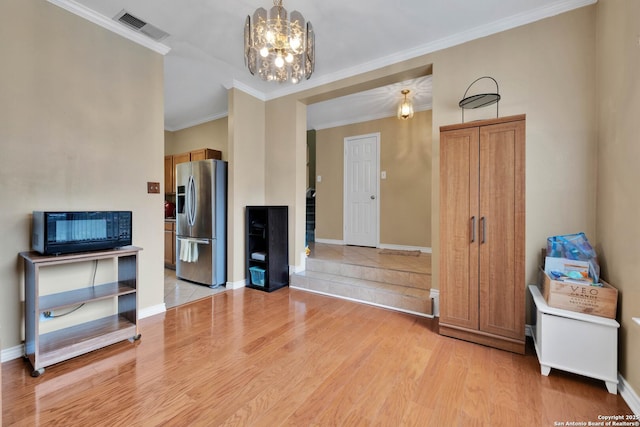 living room with crown molding, a notable chandelier, light wood-type flooring, and visible vents
