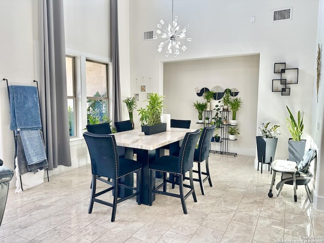 dining room with visible vents, marble finish floor, a high ceiling, and a chandelier