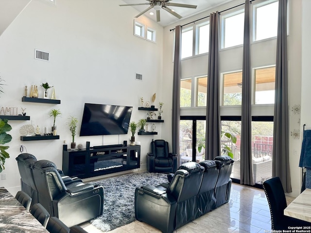 living area featuring a ceiling fan, visible vents, and a towering ceiling