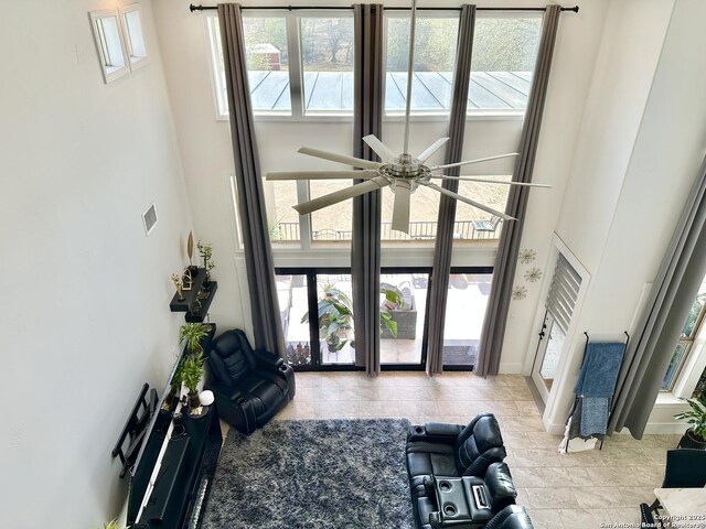 living area featuring baseboards, a high ceiling, and ceiling fan