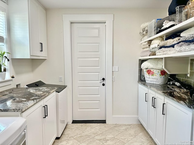 interior space with washer and dryer, open shelves, dark stone counters, and white cabinets