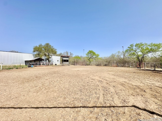 view of yard with fence, an outbuilding, a rural view, an enclosed area, and an exterior structure