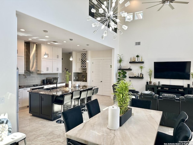 dining area featuring a towering ceiling, ceiling fan with notable chandelier, recessed lighting, and visible vents